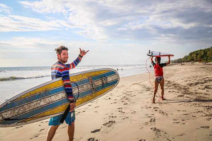costa rica tours people with surf boards on a beach smiling