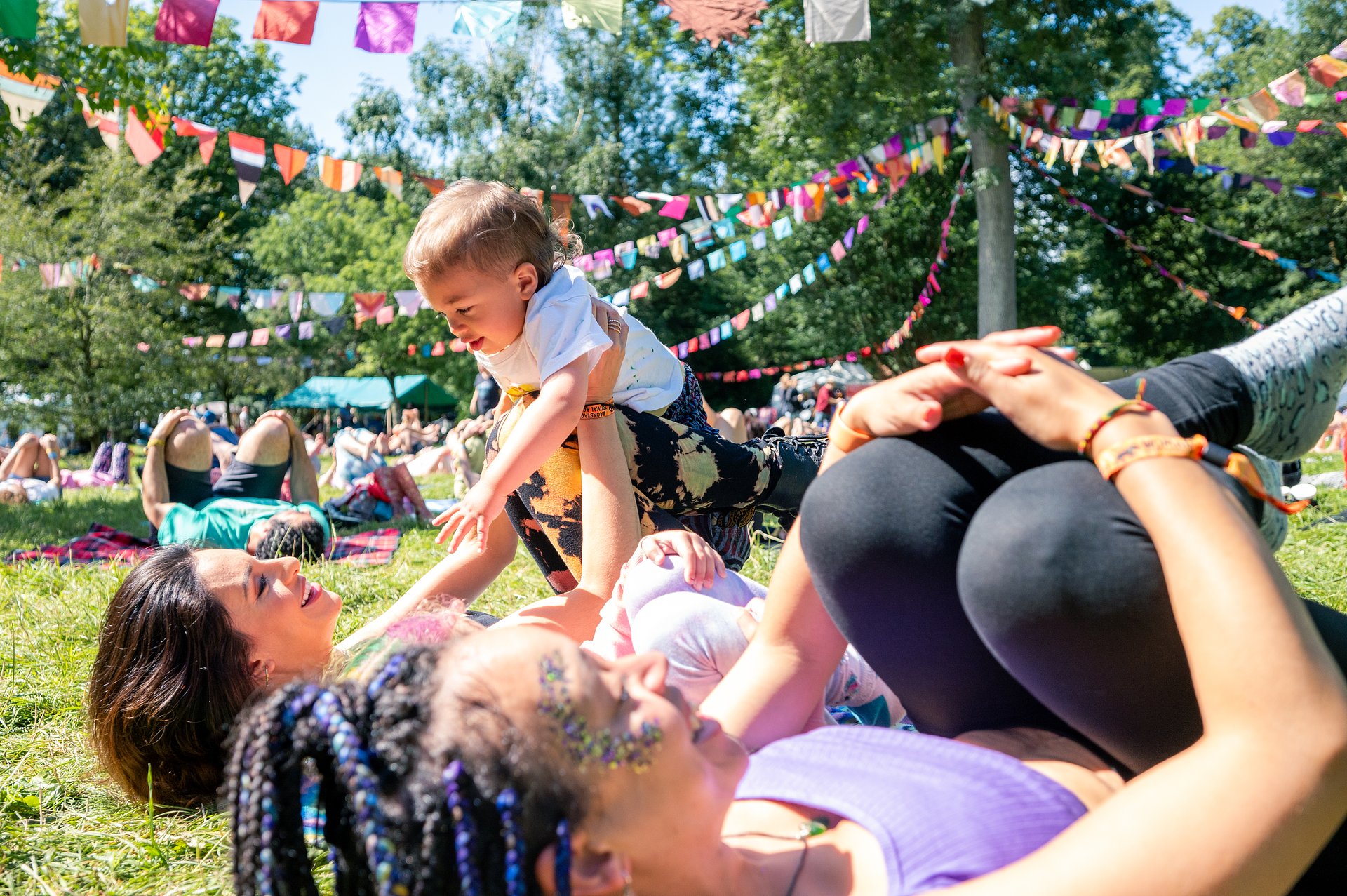 Two women taking part in yoga, lying on the floor holding up a baby