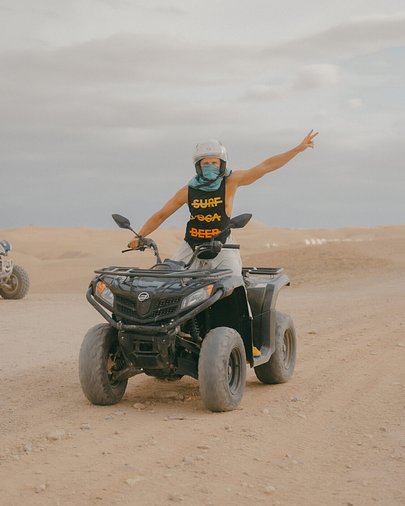 SurfYogaBeer guest standing on a quad bike in the Moroccan desert