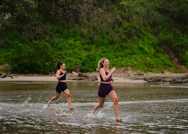 Two women racing into the ocean