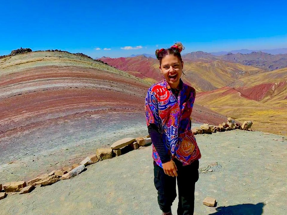 A traveller on Palccoyo rainbow mountain, striped slopes behind