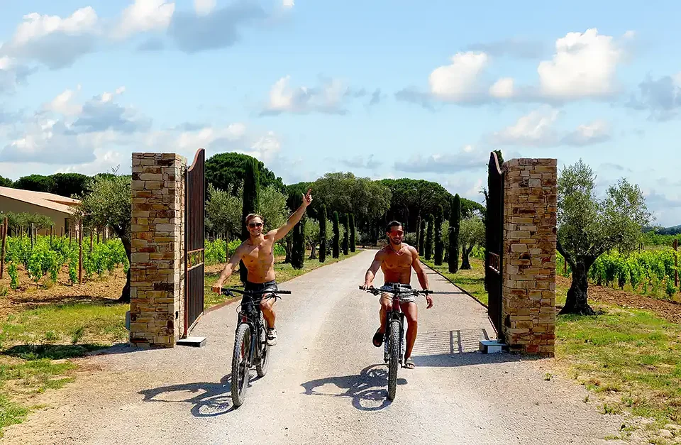 Two SYB guys riding bikes through the gates of a Provence winery