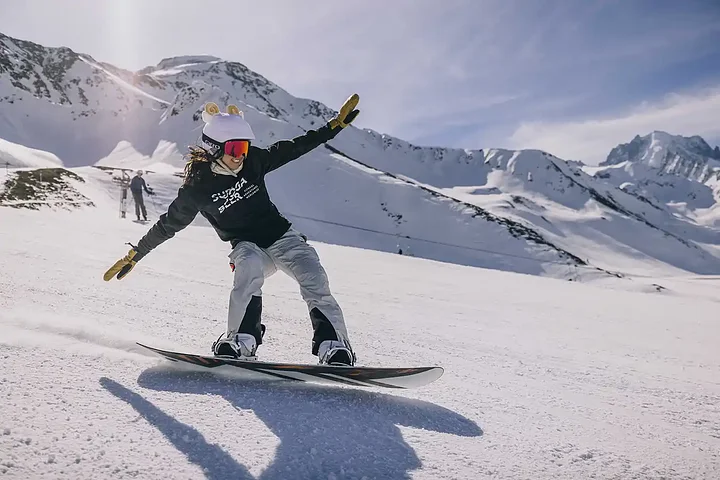 An SYB guest riding a snowboard on the piste