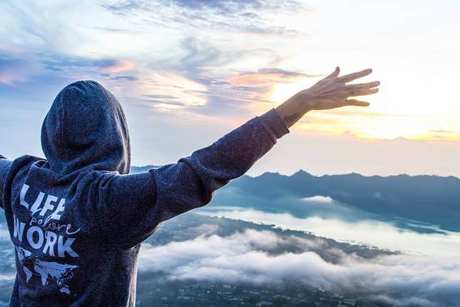 person with their arm in the air taking a photo at sunrise bali