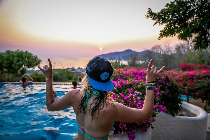 girl facing backwards with hands up giving a rad sign with sunset in background nicaragua all inclusive