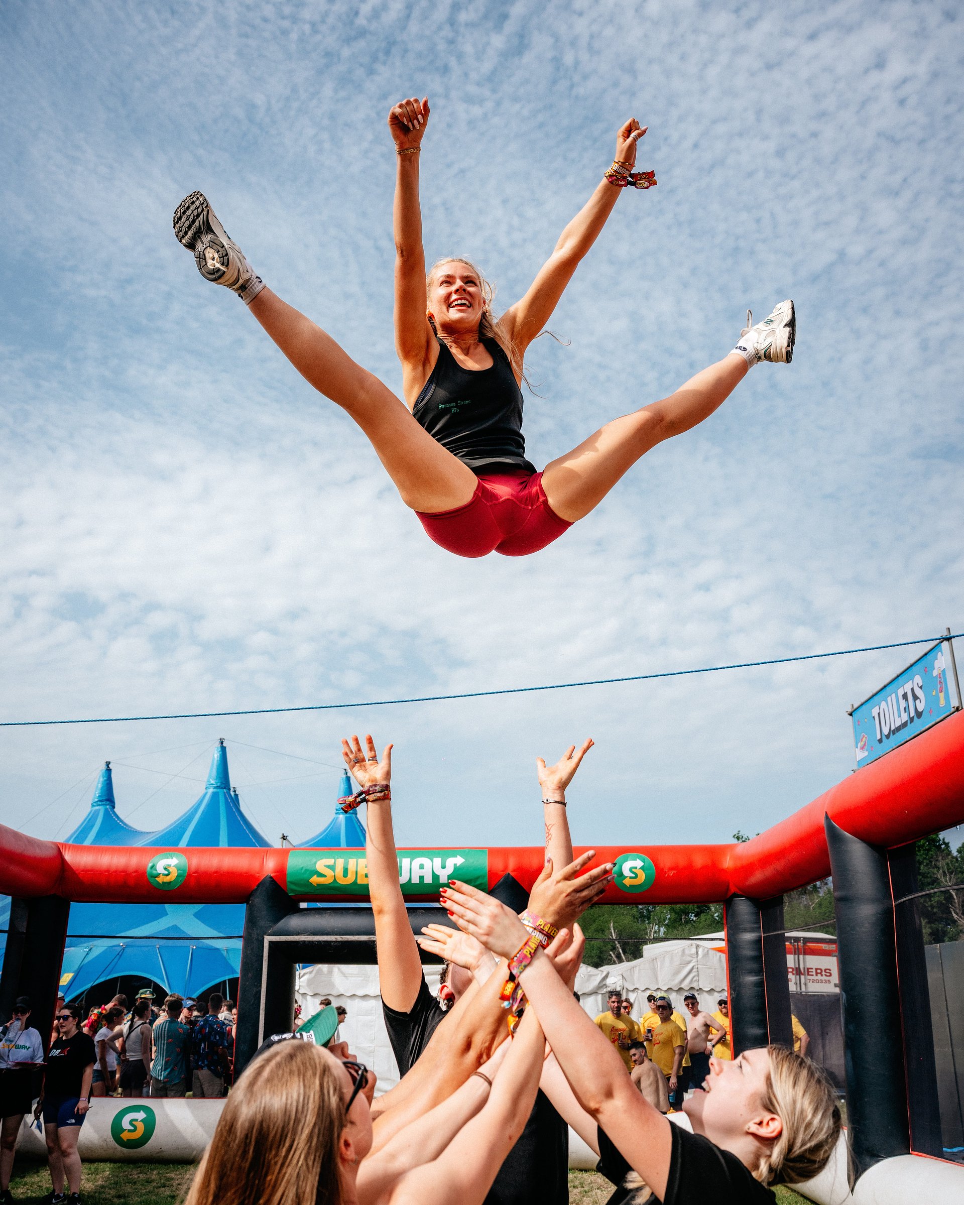 Dodgeball team throw their female player into the air in celebration at Bournemouth 7s Festival, in Dorset.
