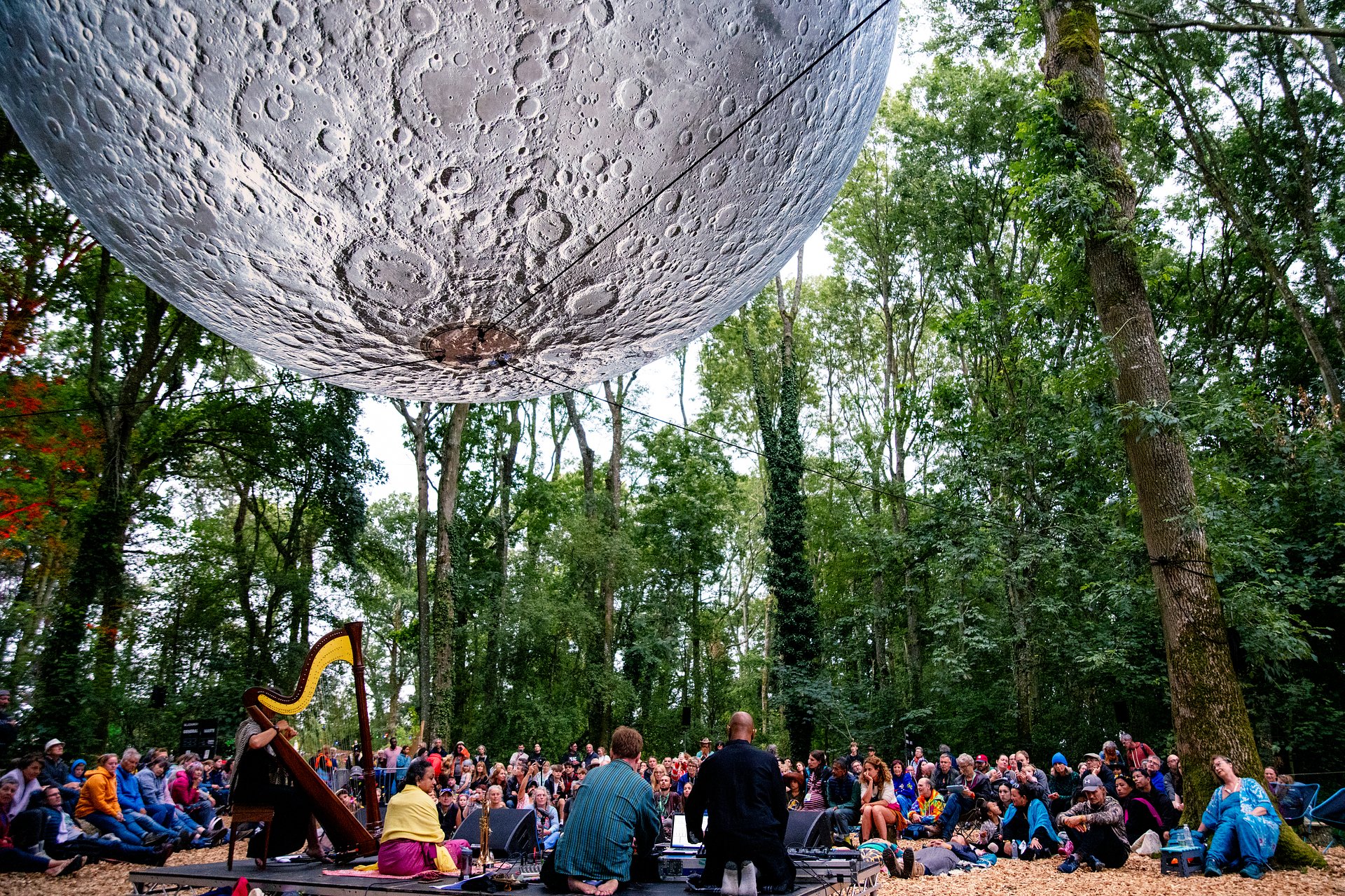 A crowd sat under The Moon installation in the secret forest