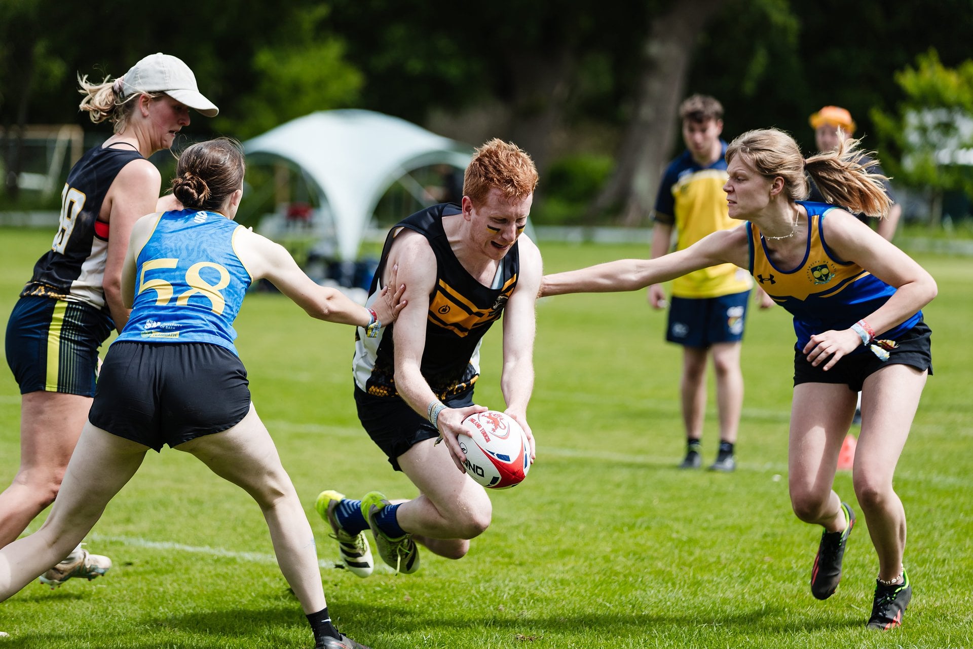 Mixed touch rugby action at Bournemouth 7s Festival in Dorset, with a player carrying the ball as an opponent attempts a tackle.