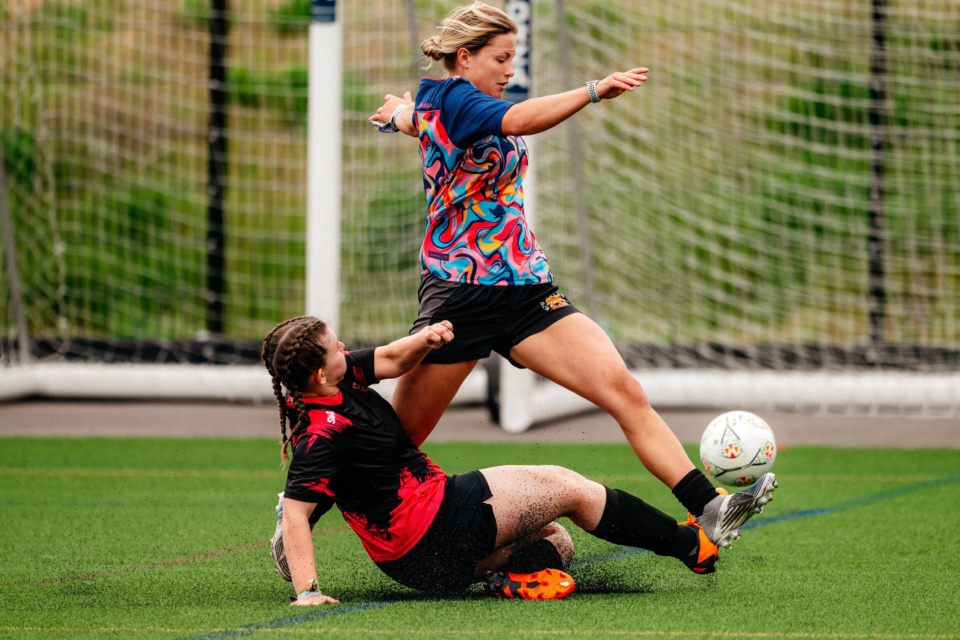 Women's football player jumps a slide tackle during a 6-a-side women's football tournament at Bournemouth 7s Festival, in Dorset.