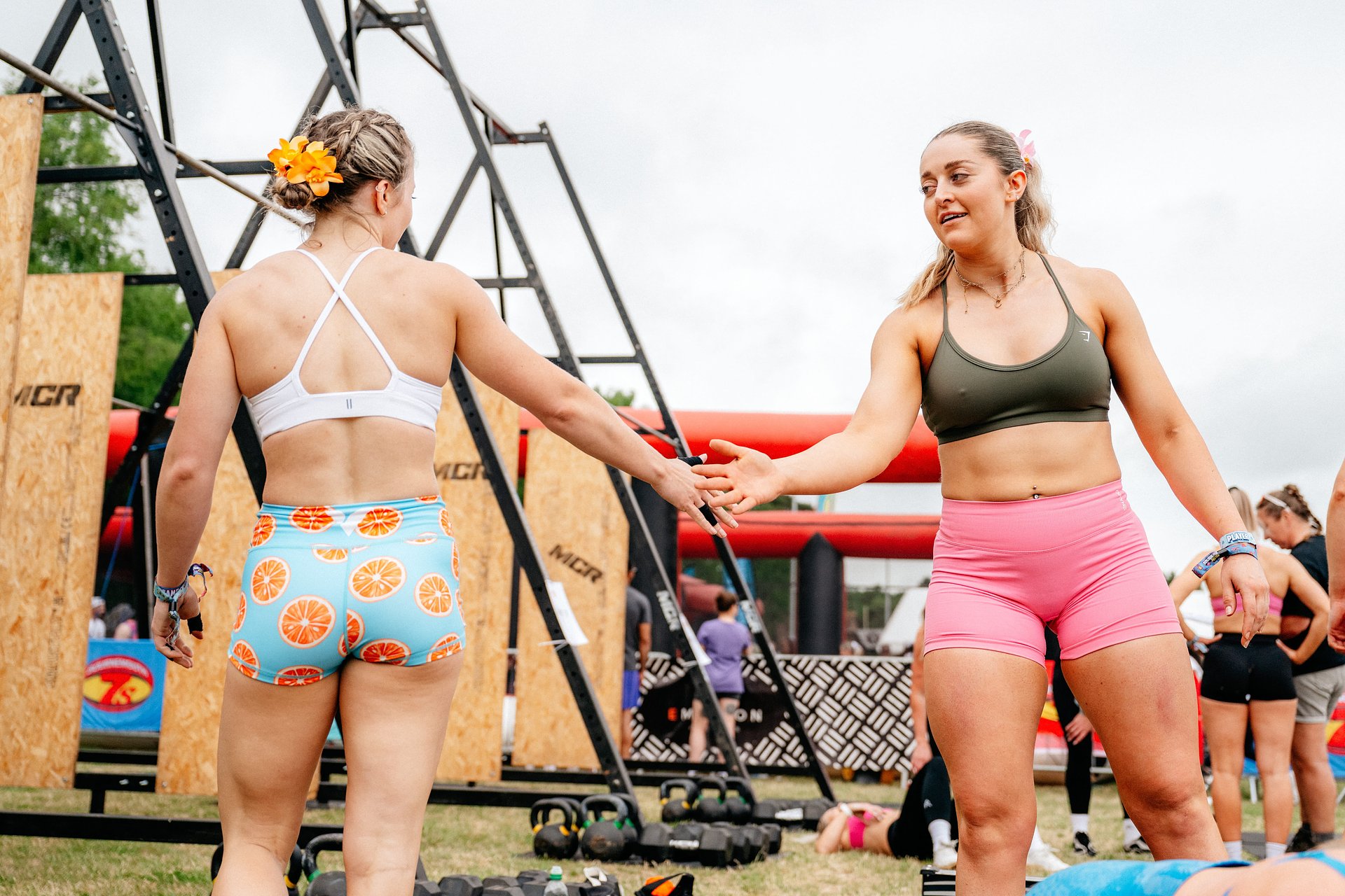 Two girls slap hands in celebration after completing a workout at the Fitness Games competition, at Bournemouth 7s Festival.