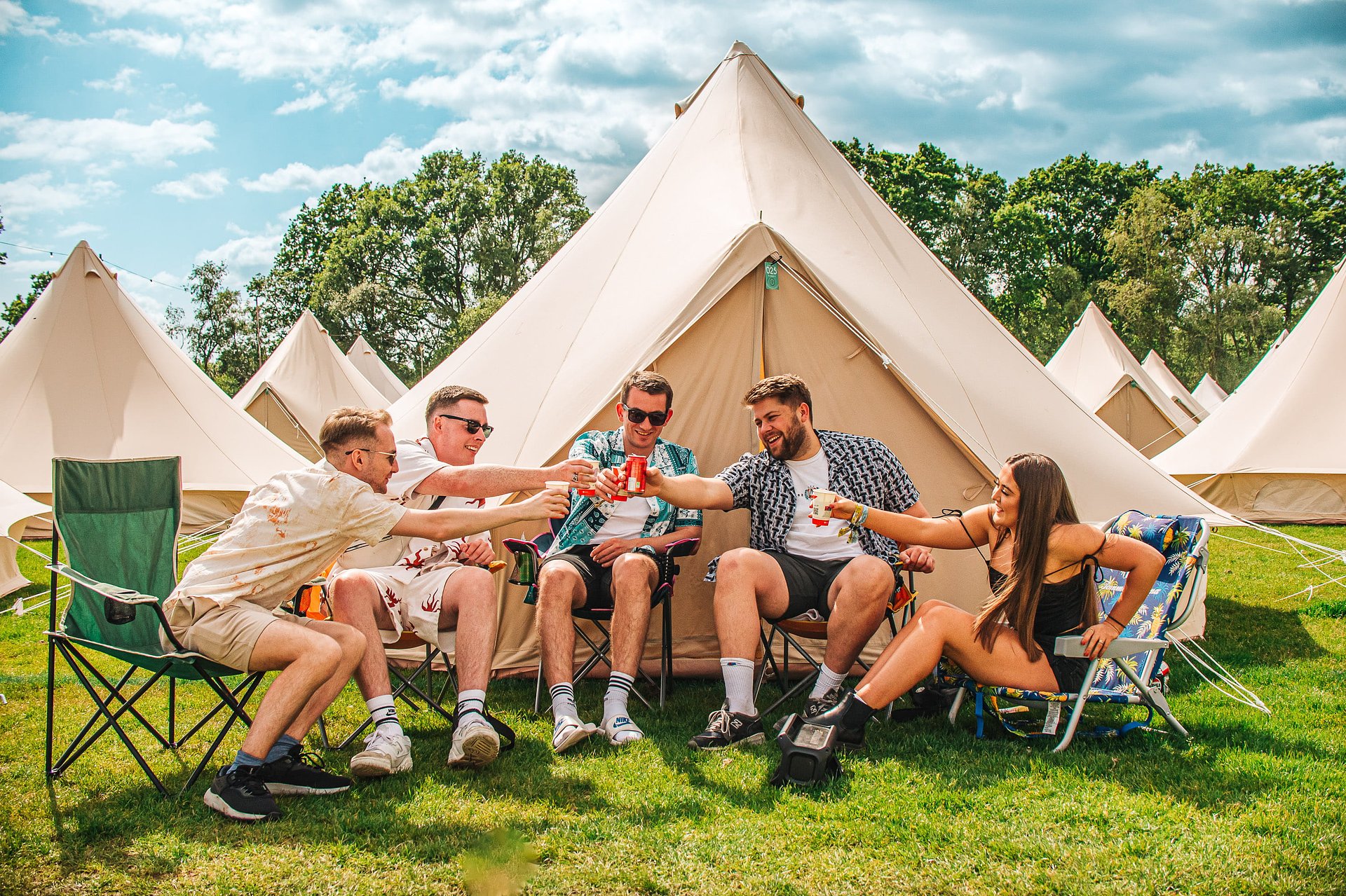 Candid group of friends having drinks in front of their Glamping bell tent at Bournemouth 7s Festival