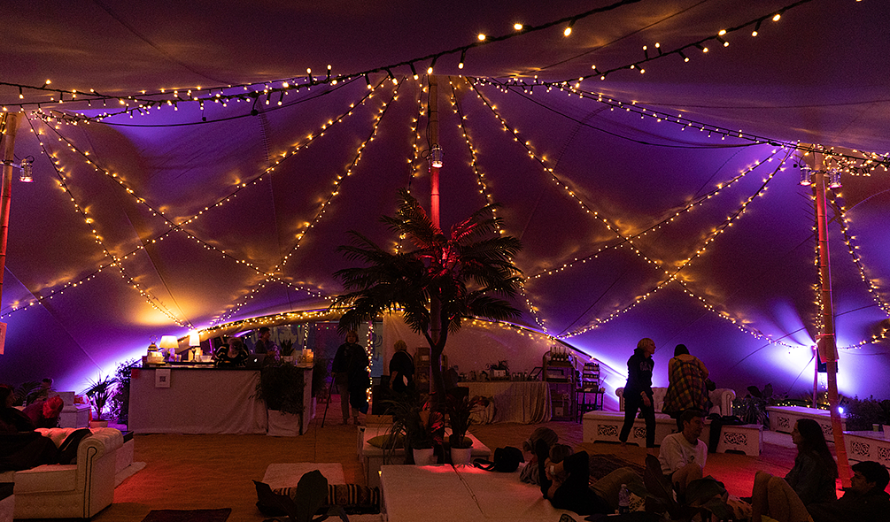 the Spa tent in the dark, lit up by purple lights and yellow fire lights