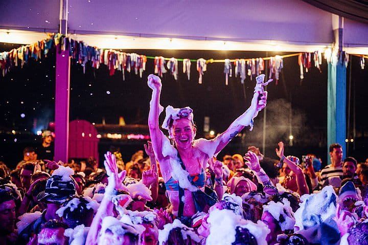 Girl on shoulders dancing to the music during the foam party in the VIP arena at Bournemouth 7s Festival in Dorset