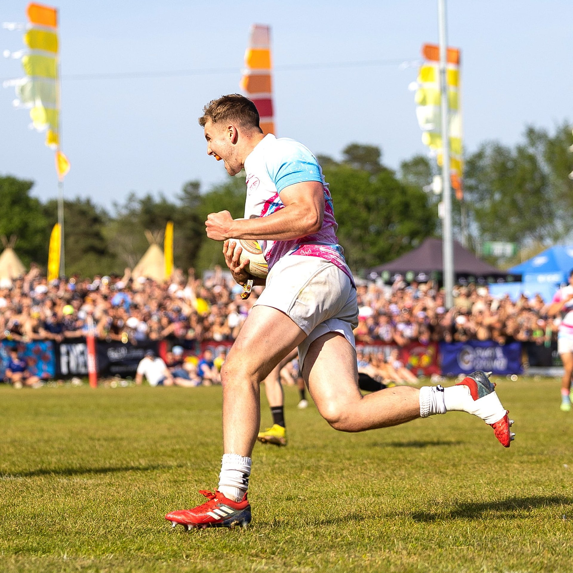 Rugby player sprinting across the pitch with the ball in front of a large crowd at Bournemouth 7s Festival, in the Mens National Cup Final..