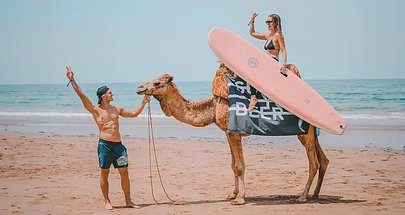 SurfYogaBeer guest with a surfboard on the beach in Taghazout