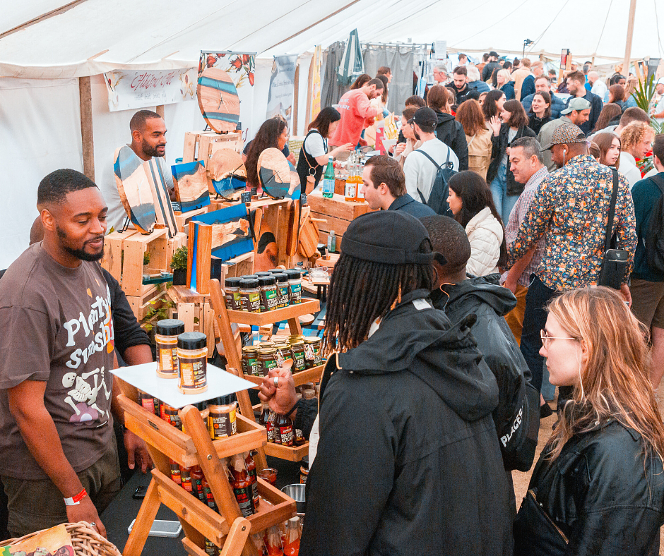 An artisan stall at Savour London featuring and poca jams and Godminster cheese with a lady buying them 