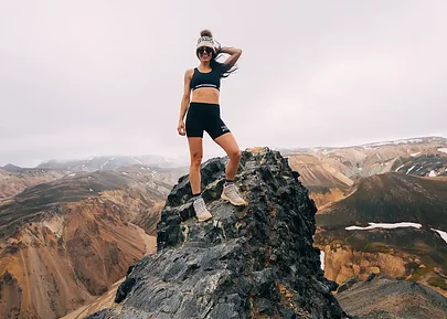 A trail runner standing on a rock high in the Icelandic mountains