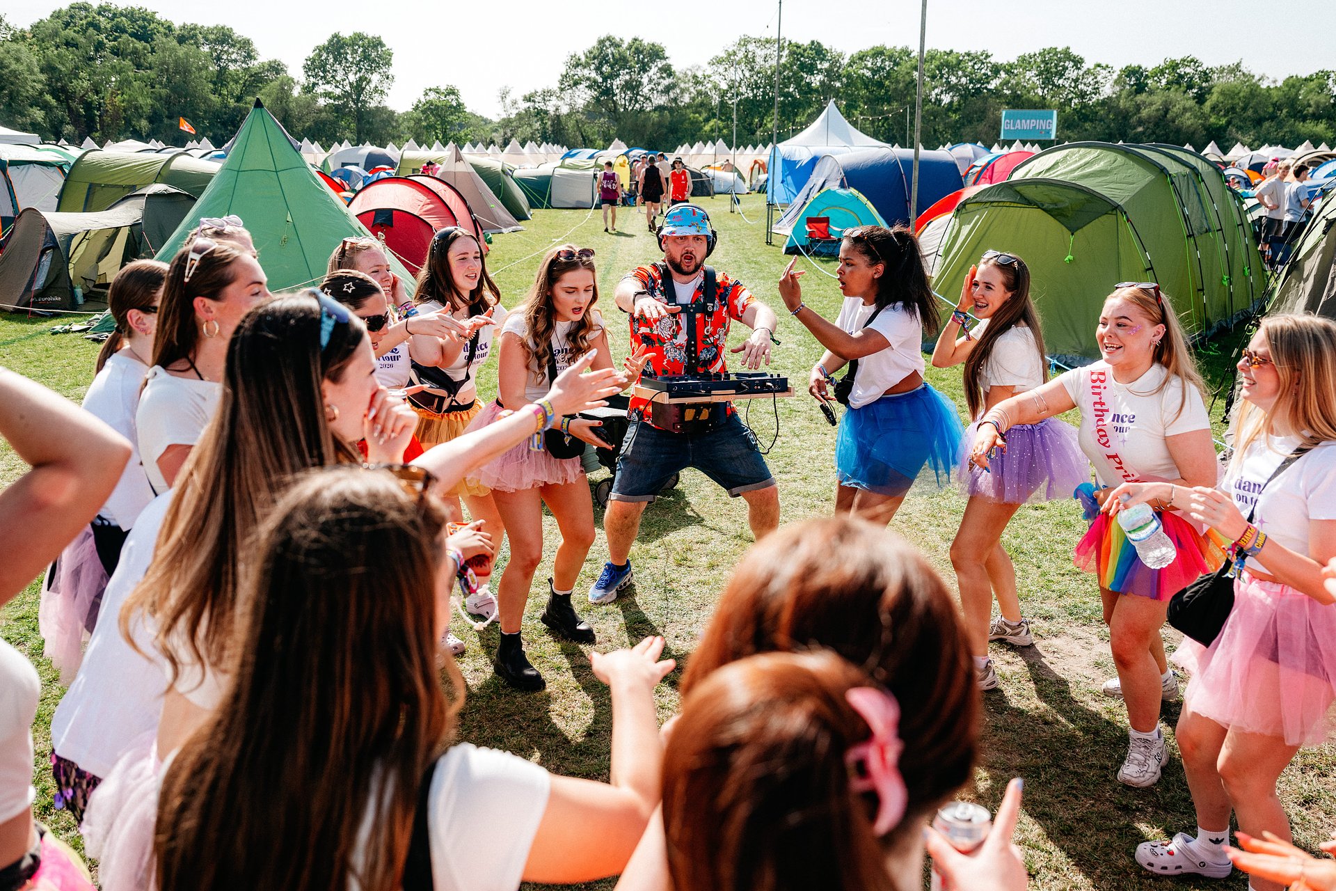 Group of girls dance with roaming campsite DJ inside the camping area at Bournemouth 7s Festival, in Dorset