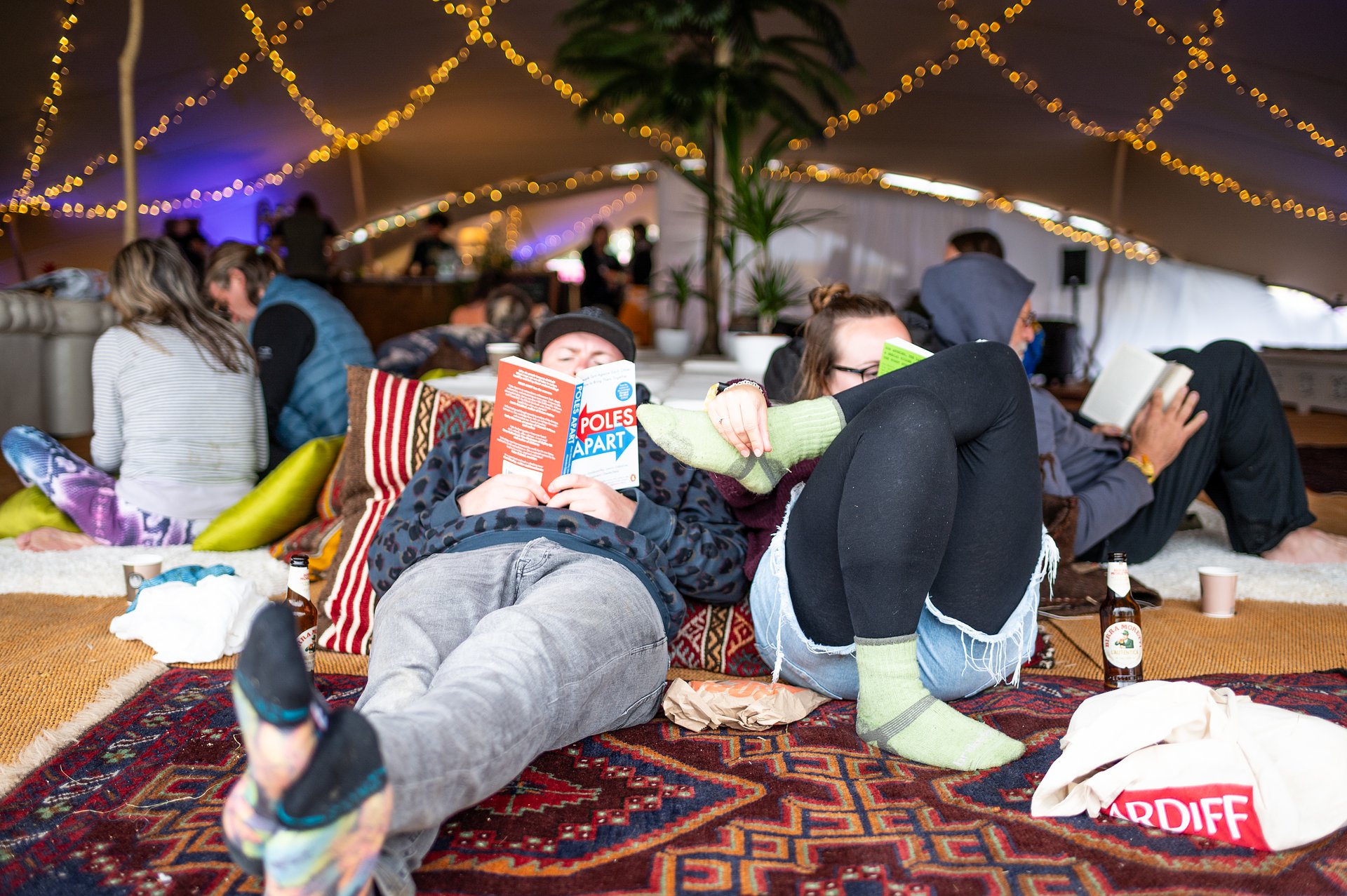 Two people lying on the floor in the spa tent reading books