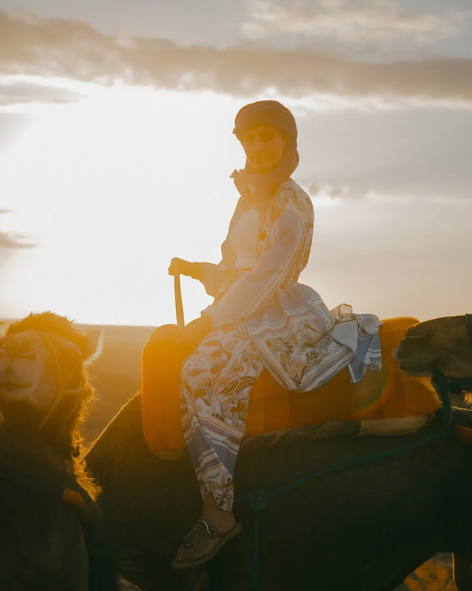 A traveler riding a camel, backlit at sunset in the Sahara
