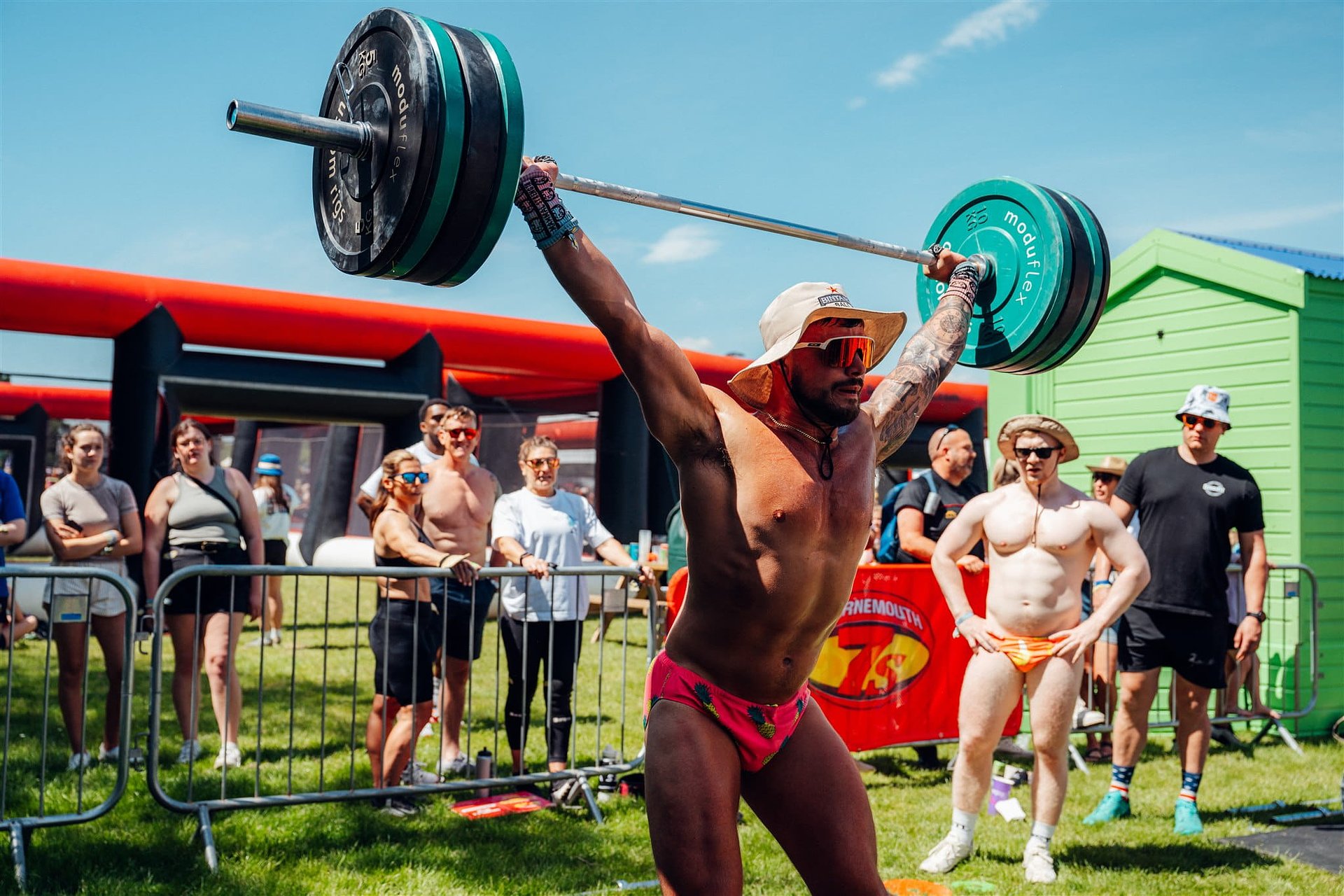 Man competing in the annual Fitness Games competition at Bournemouth 7s Festival, doing an overhead clean lift.