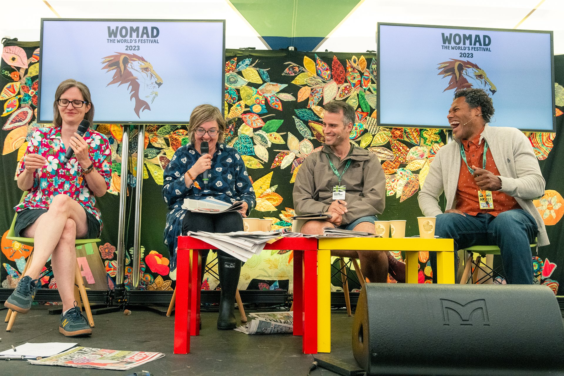 a panel of 4 people sat on stage in the world of words tent. They are laughing and speaking to an audience.