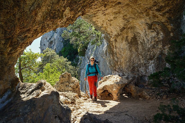71022594AyoungwomanwithtrekkinggearhikingthroughtherockarchArcusuFeilauatthemountainouscoastabove