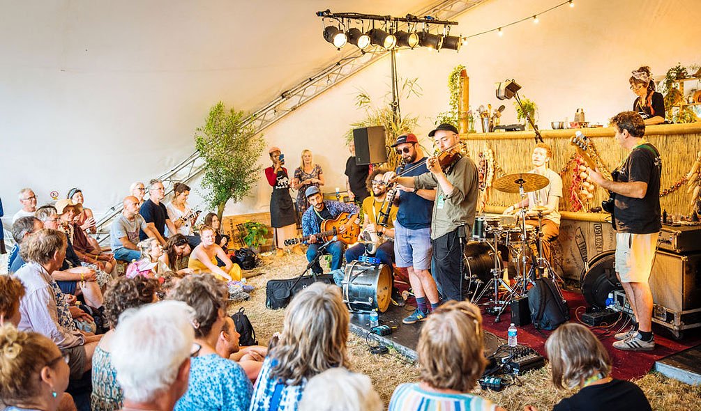 a band made up of a fiddle player, drummer, guitarist and clarinet player performing at the Taste the World stage