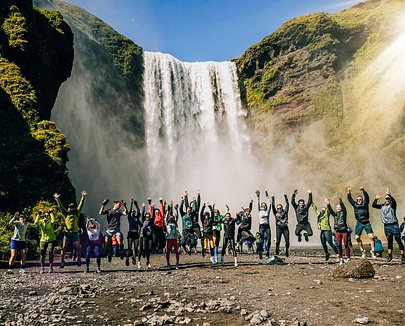 SurfYogaBeer traveler standing under an Icelandic waterfall
