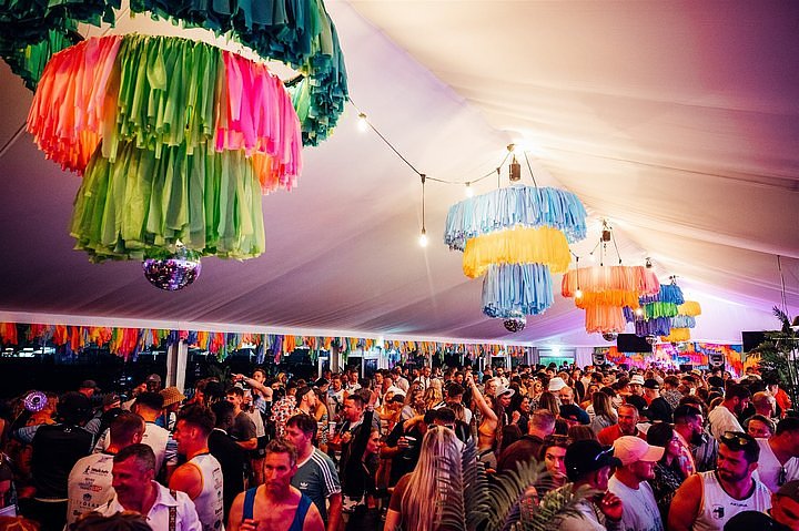 Inside the V.VIP arena for exclusive hospitality with colourful chandeliers, a large crowd dancing at Bournemouth 7s Festival.