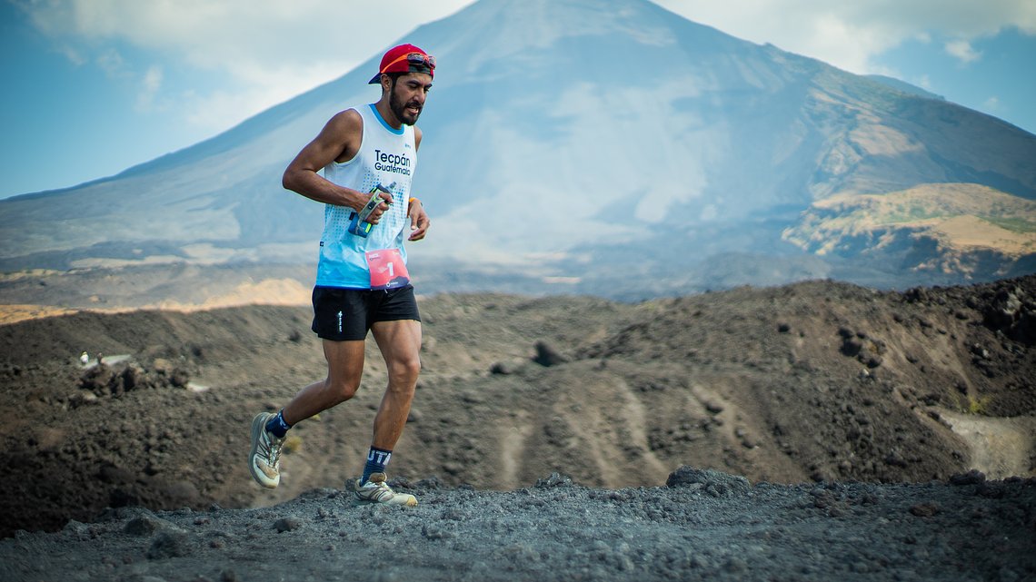 Runner navigating a rugged lava field formed by Pacaya Volcano’s 2010 eruption during an Impact Marathon event, set against stunning volcanic scenery.